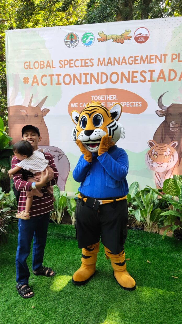 Seorang anak digendong ayahnya berfoto bersama manusia boneka harimau